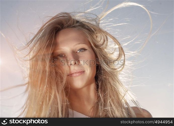 Young gender fluid person with long blond hair fly with the wind retro color sun flares