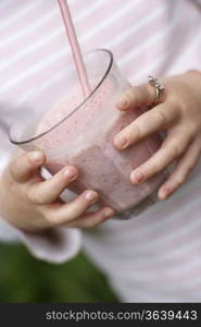 Young girl (5-6) holding glass with smoothie mid section