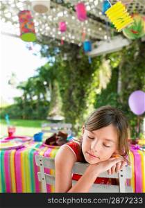 Young girl (7-9) sleeping on patio after birthday party close-up
