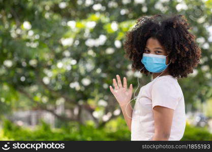 Young girl afro in face mask going at reopen school after covid-19 quarantine and lockdown. It is new normal for protection and prevention while outbreak of coronavirus or flu. back to school concept.