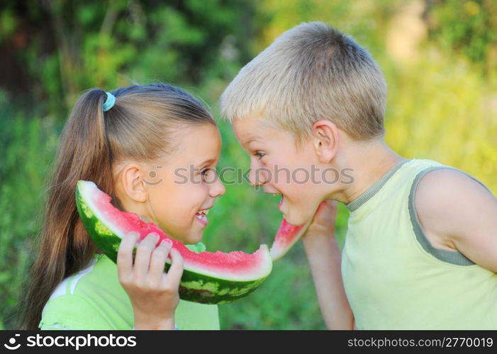 Young girl and boy eating watermelon in the park