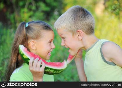Young girl and boy eating watermelon in the park