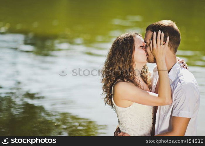 Young girl and guy kissing on the background of the water of the pond.. Kiss on the shore of the pond 6318.