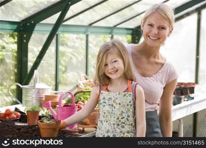 Young girl and woman in greenhouse smiling