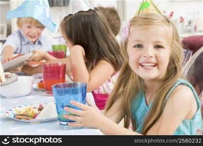 Young girl at party sitting at table with food smiling