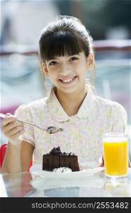 Young girl at restaurant eating dessert and smiling (selective focus)