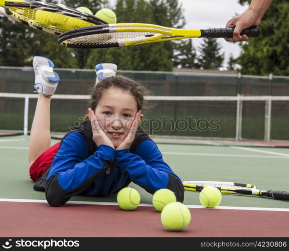 Young girl being given acceptance into tennis group with rackets over her head