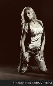 young, girl, blonde, jeans, clothes on a dark background kneels