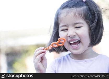 Young girl blowing bubbles, laughing, close-up