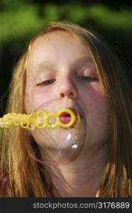 Young girl blowing soap bubbles - one big bubble