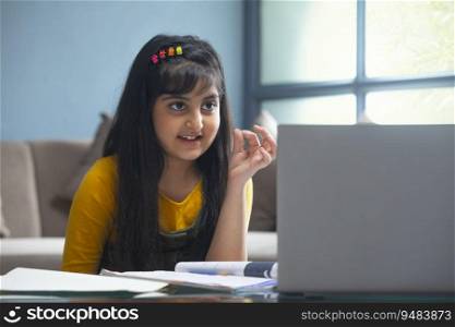 Young girl calculating numbers on her fingertips in front of her laptop during online class
