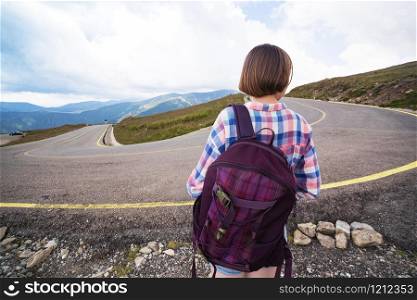 Young girl coming along the road and hitch-hiking