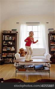Young girl dancing on top of coffee table