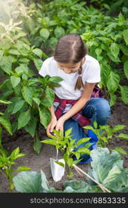 Young girl digging earthing soil at vegetable garden bed