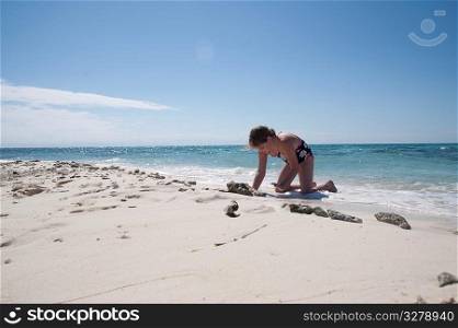 Young girl digging in sand on beach at Belizean Isle in Belize