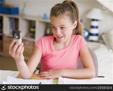 Young Girl Distracted From Her Homework, Playing With A Cellphone