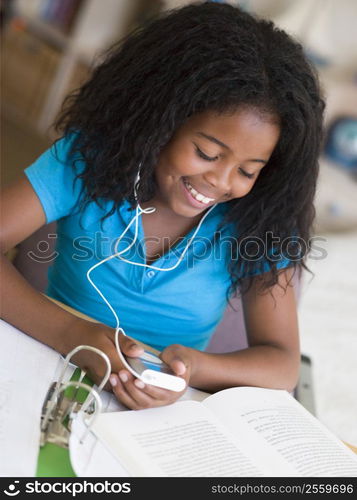 Young Girl Distracted From Her Homework, Playing With An MP3 Player