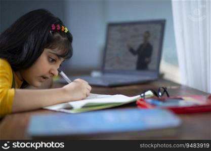 Young girl doing her work while attending virtual class