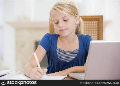 Young Girl Doing Homework And Using Laptop