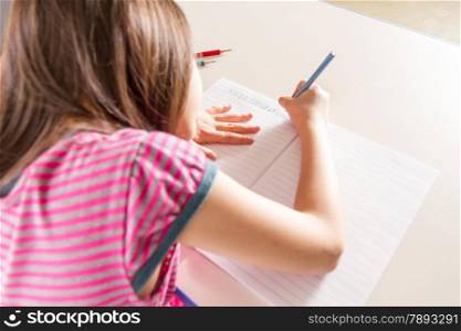 Young girl doing homework in a notebook