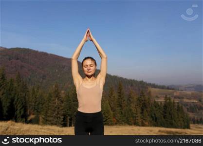 Young girl doing yoga fitness exercise outdoor in beautiful mountains landscape. Morning sunrise, Namaste Lotus pose. Meditation and Relax. Healthy Lifestyle. Young girl doing yoga fitness exercise outdoor in beautiful mountains landscape. Morning sunrise, Namaste Lotus pose. Meditation and Relax. Healthy Lifestyle.