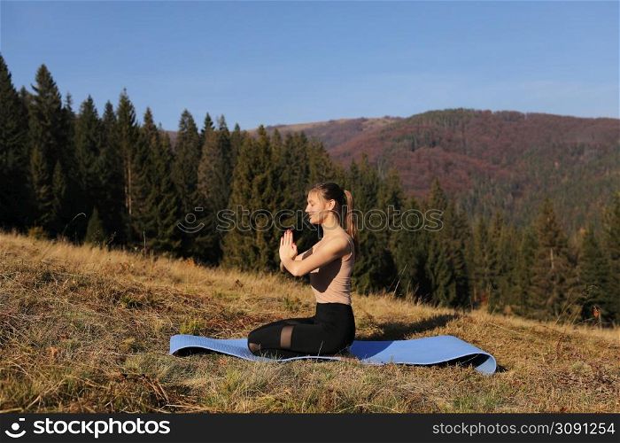 Young girl doing yoga fitness exercise outdoor in beautiful mountains landscape. Morning sunrise, Namaste Lotus pose. Meditation and Relax.. Young girl doing yoga fitness exercise outdoor in beautiful mountains landscape. Morning sunrise, Namaste Lotus pose. Meditation and Relax