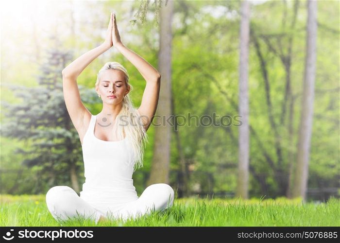 Young girl doing yoga in park. Young girl doing lotus yoga exercise in spring park
