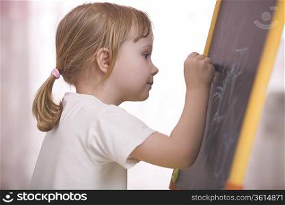 Young girl drawing on chalkboard