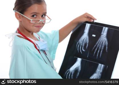 Young girl dressed in hospital scrubs examining an X ray