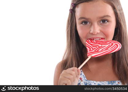 Young girl eating a heart shaped lolly