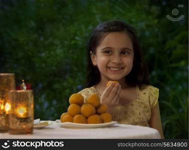 Young girl eating a laddoo