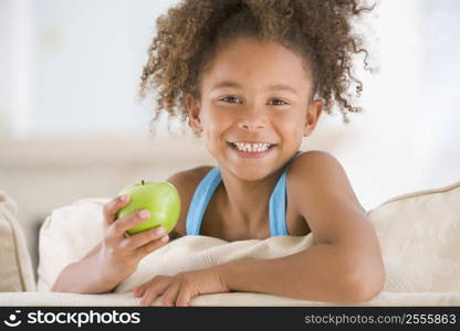 Young girl eating apple in living room smiling