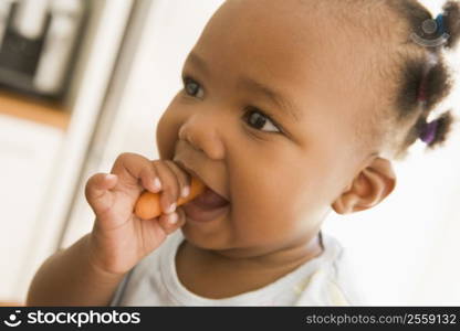 Young girl eating carrot indoors
