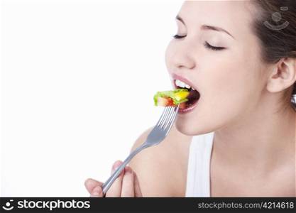 Young girl eating salad on a white background