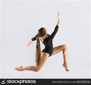 Young girl engaged art gymnastic on grey