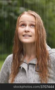 Young girl enjoys rain in the park. Close up portrait.