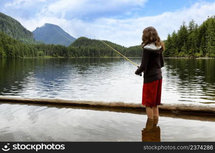 Young girl fishing in mountain lake while wadding in water