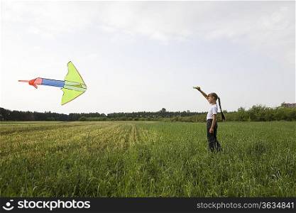 Young girl flying kite in field