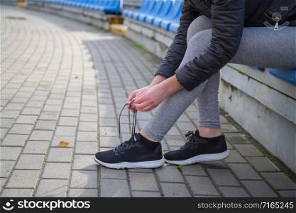 young girl getting ready for a run through the stadium and tying shoelaces on sports shoes. girl tying shoelaces