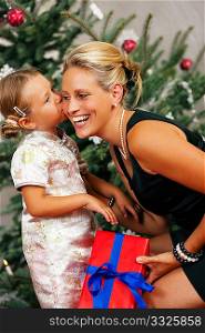 Young girl gives a gift to her mother, kissing her