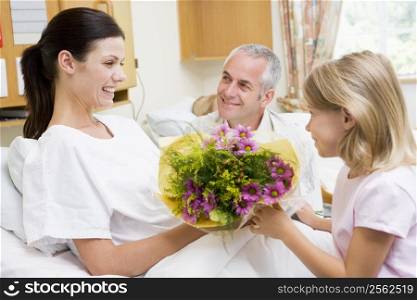Young Girl Giving Flowers To Her Mother In Hospital