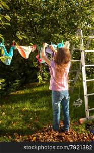 Young girl hanging clothes on clothesline at garden
