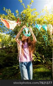 Young girl hanging clothes with clothespins at sunny day