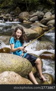 Young girl having fun fishing barefoot on stream in woods during summer