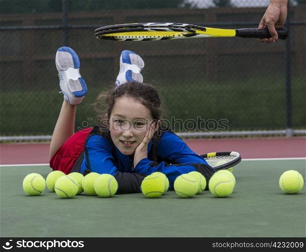 Young girl having fun on outdoor tennis courts with coach?s racket above her head