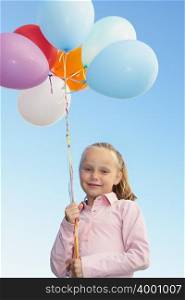 Young girl holding a bunch of balloons
