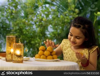 Young girl holding a laddoo