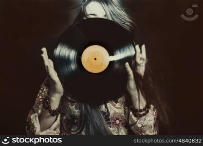 Young girl holding a vinyl record on black background