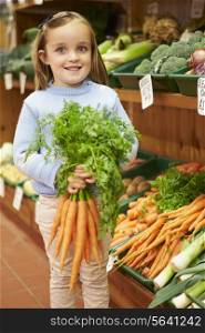 Young Girl Holding Bunch Of Carrots In Farm Shop
