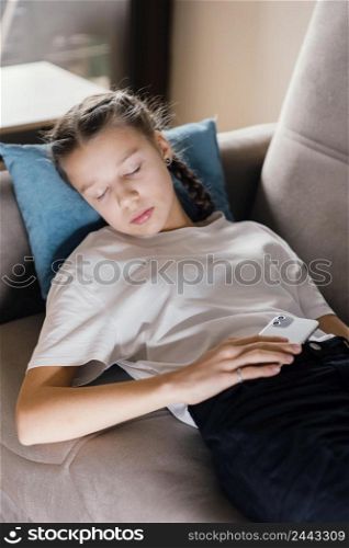 young girl holding mobile while asleep
